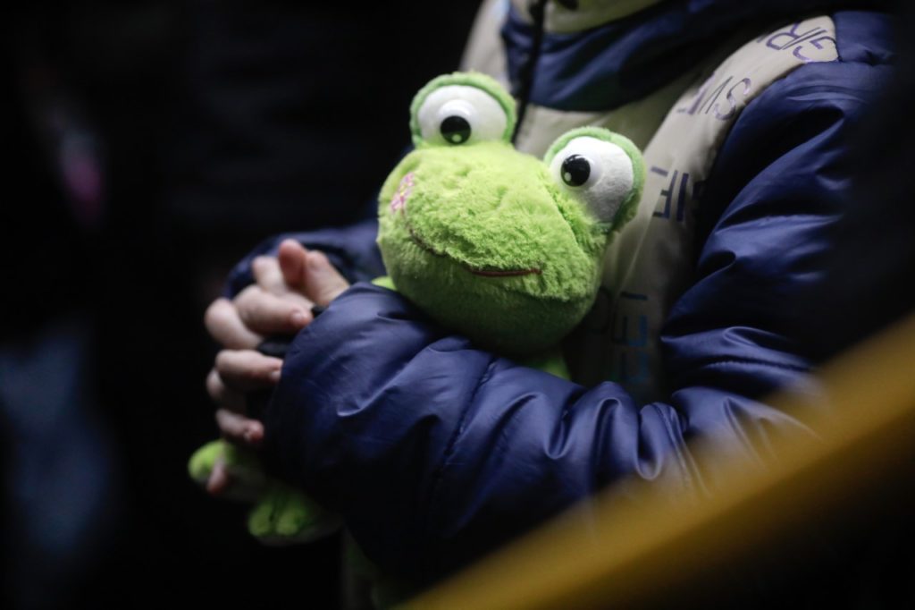 A child hugs a stuffed frog