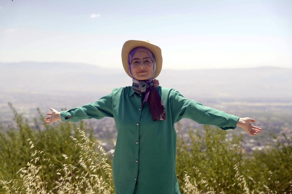 Fatima stands outside in a field