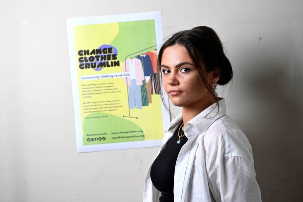 Oilean, a 23 year old woman, in front of a sign for Change of Clothes Crumlin