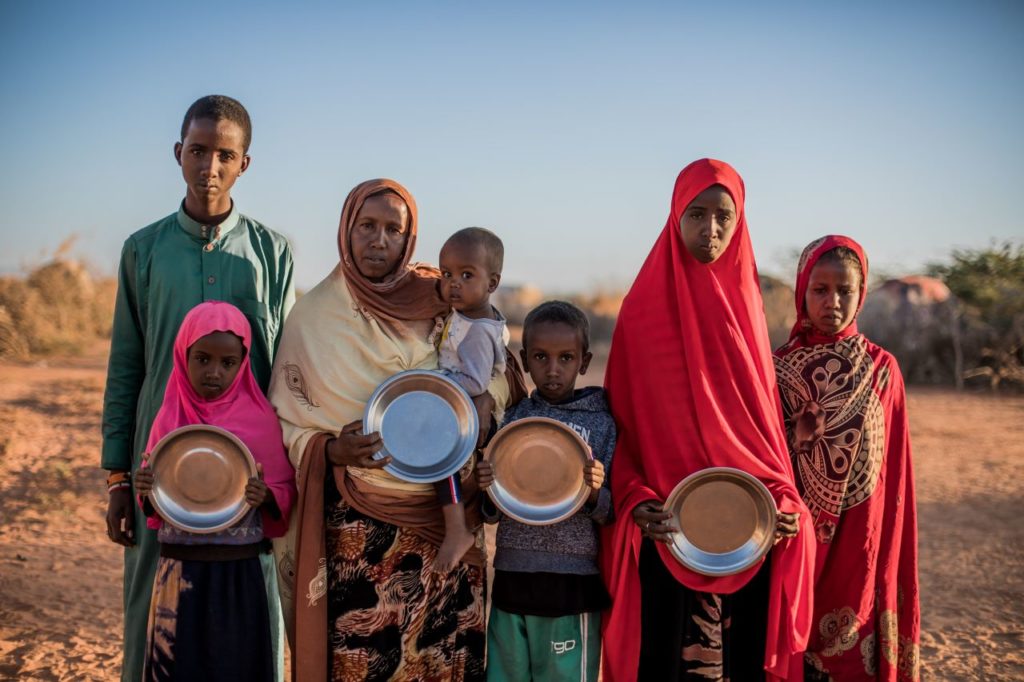 Hoodo and her six children stand with empty bowls of food