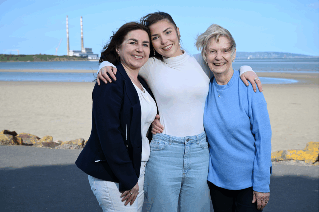Three women stand together and embrace