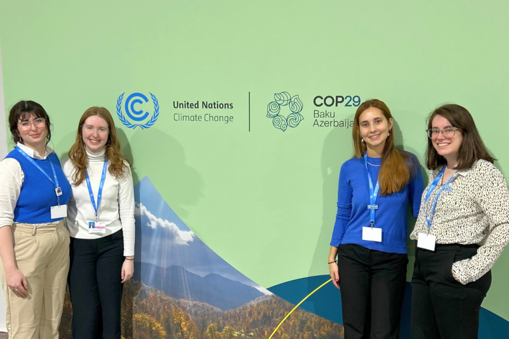 Four women standing in front of a backdrop where COP29 is written