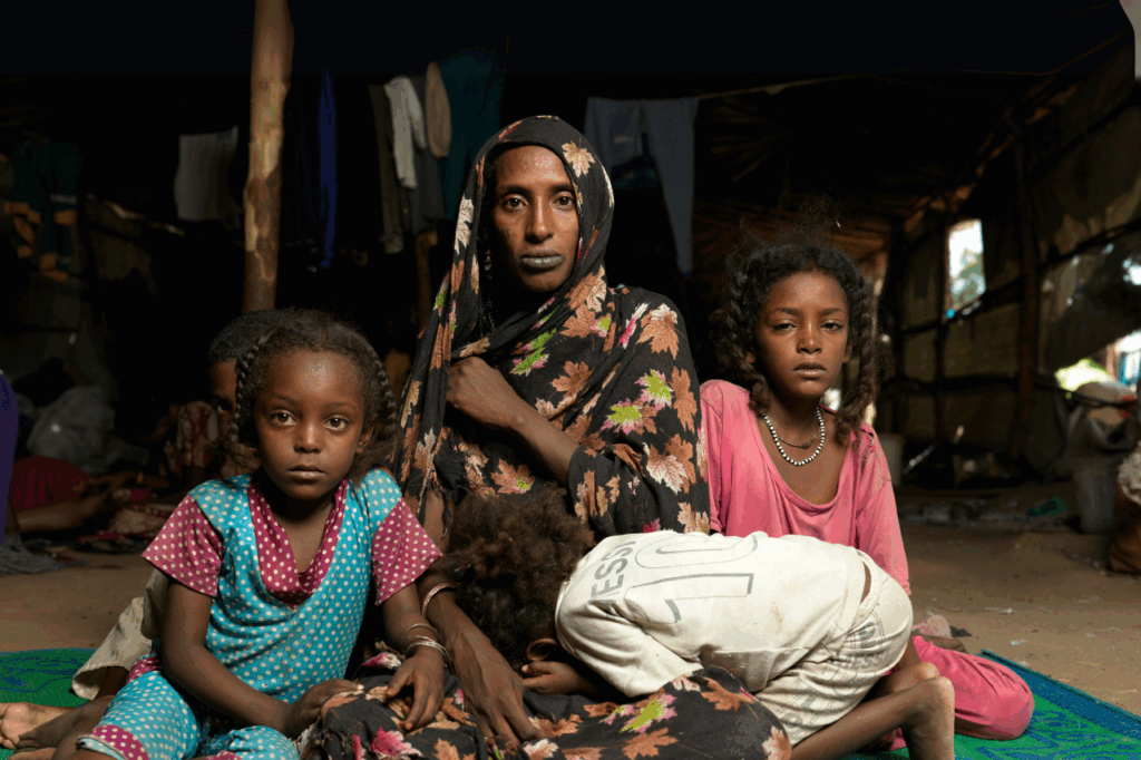 A mother and her daughters sit on the floor of their shelter