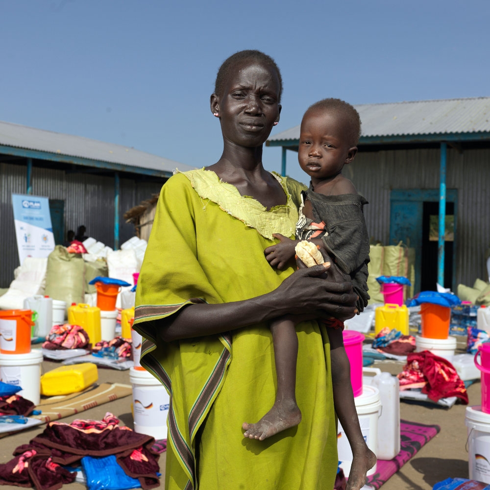 A woman in Sudan holds her child while she waits for food d