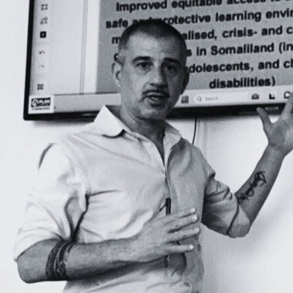A person presenting a slide on education access in Somaliland, gesturing towards the screen in a classroom setting.