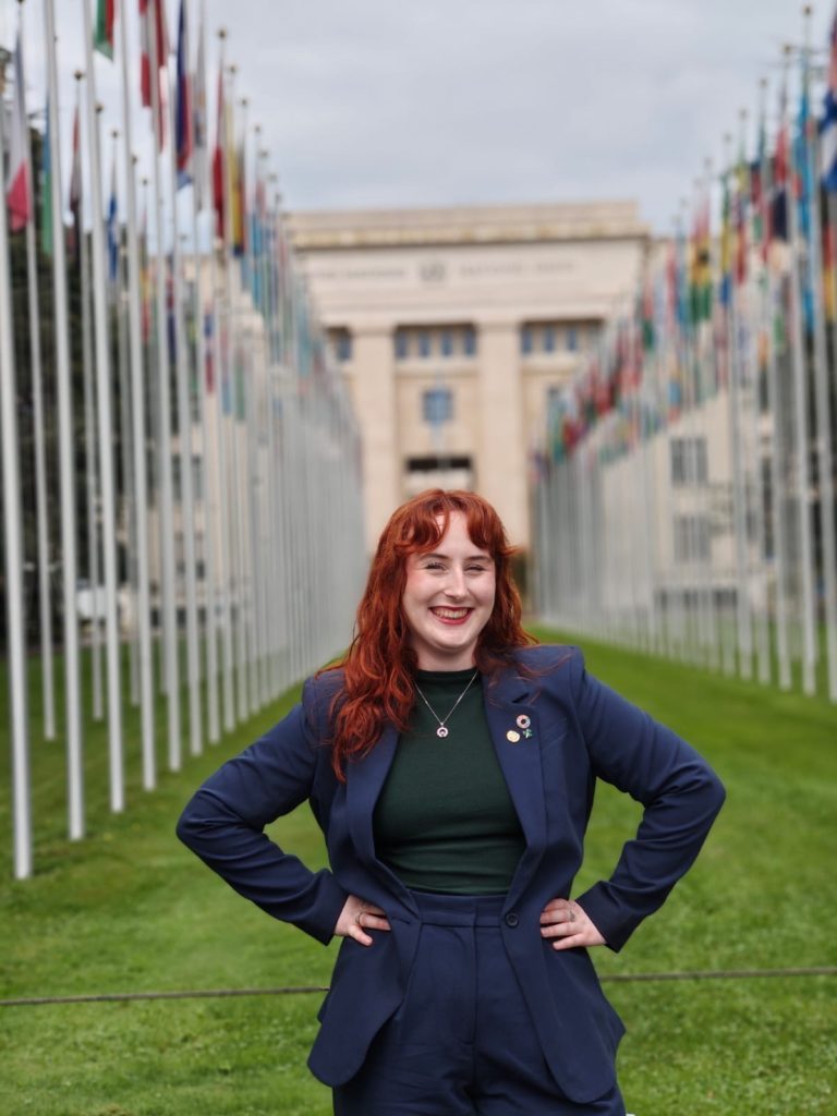 A young woman stands in front of the UN headquarters in Geneva