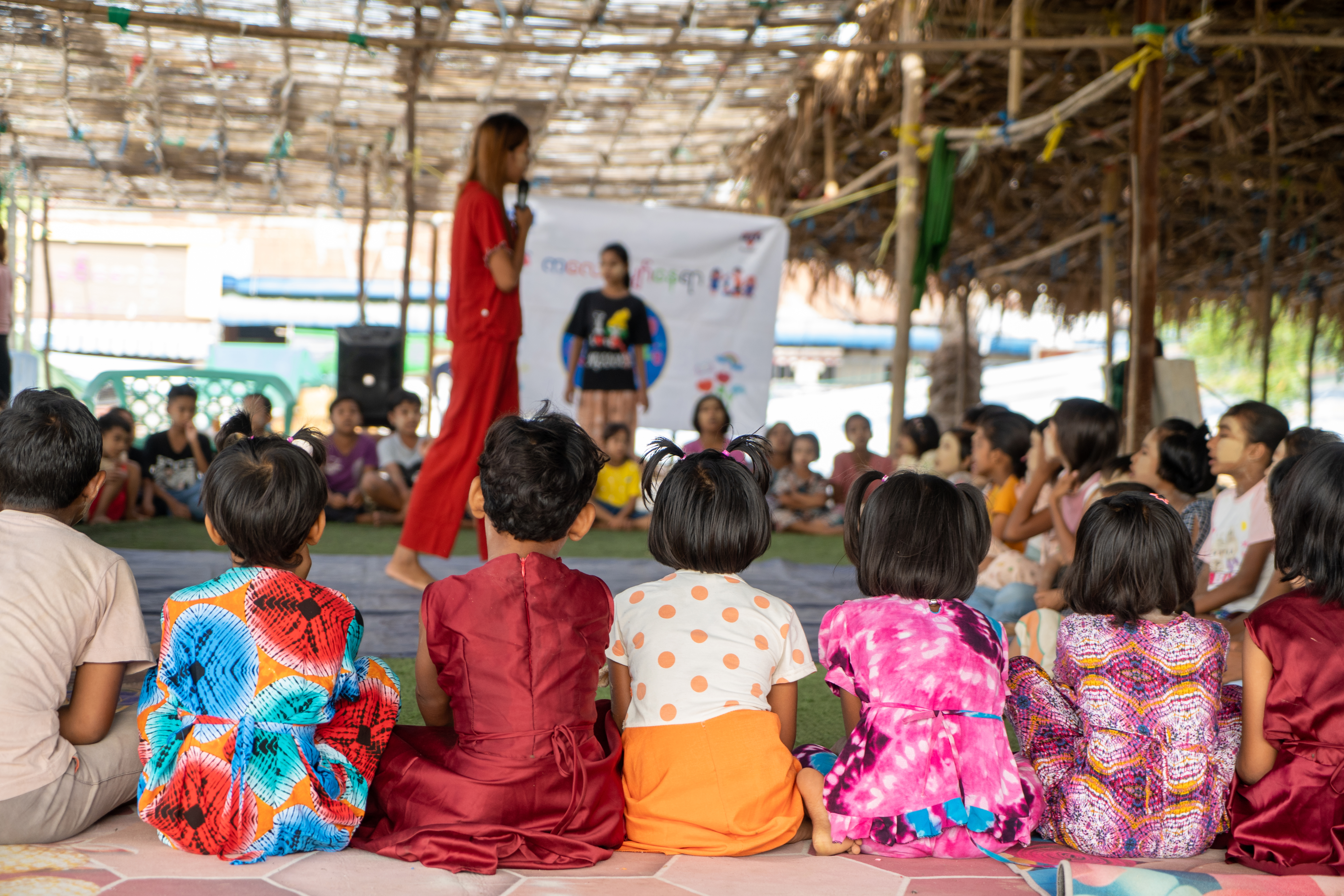 Children sit in front of a presentation in a child-friendly space