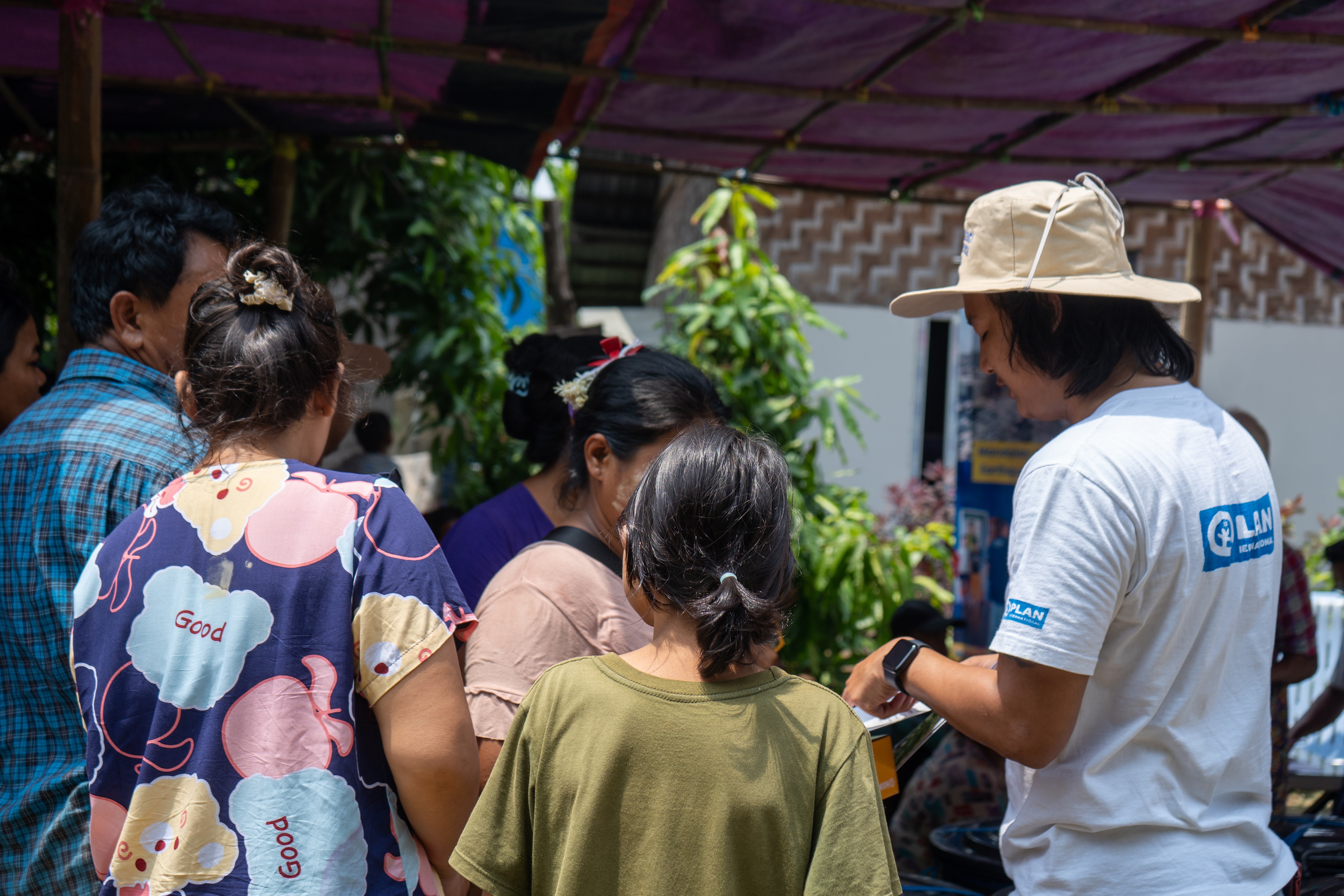 An aid worker from Plan International speaks to a group of people