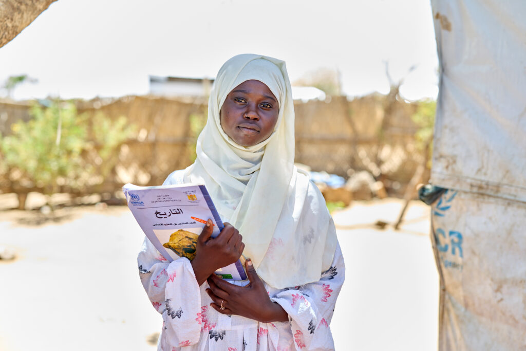 A girl in a white headscarf holds a book